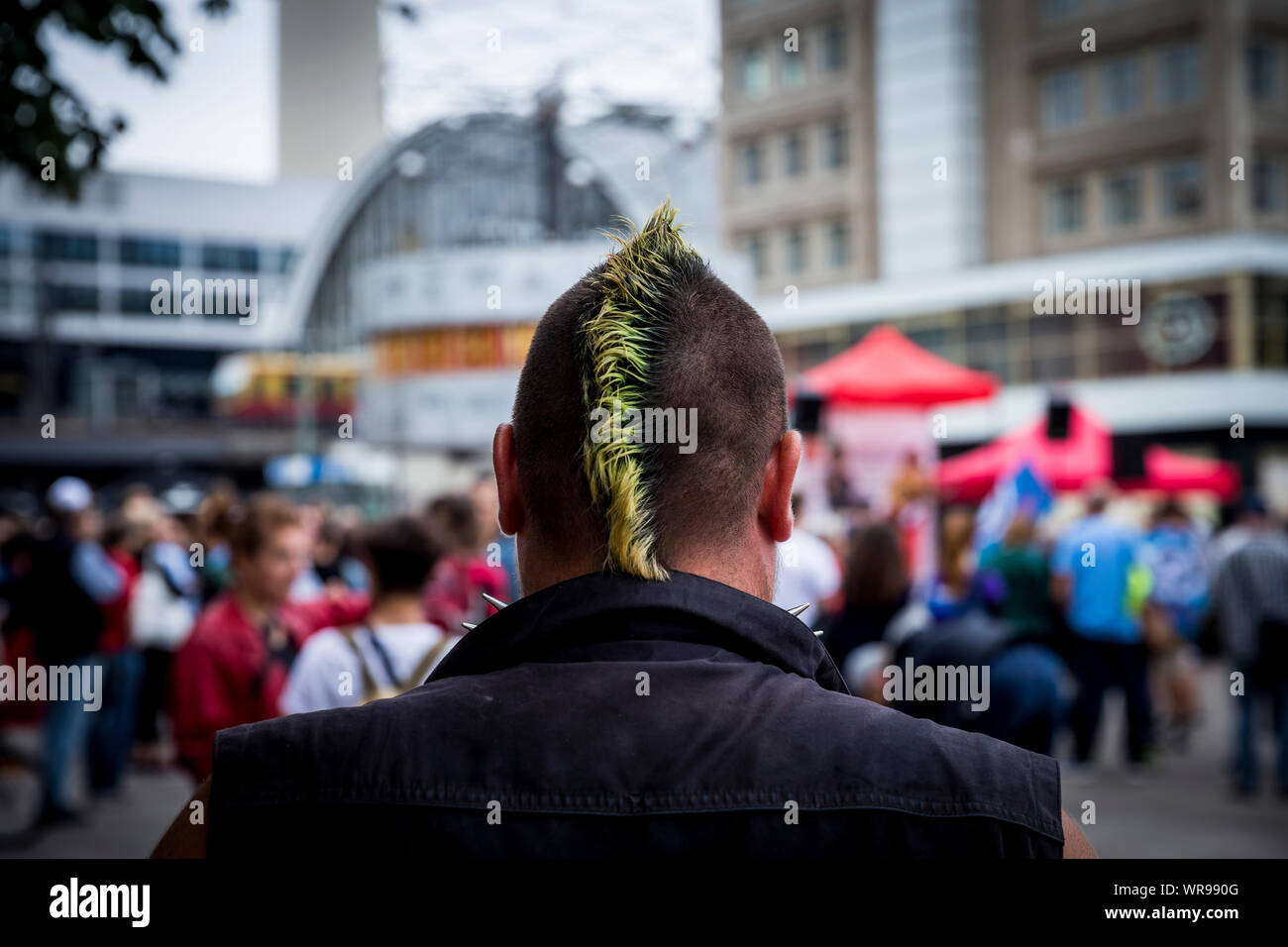 Un punk attende una dimostrazione per iniziare in Alexanderplatz di Berlino, Germania Foto Stock
