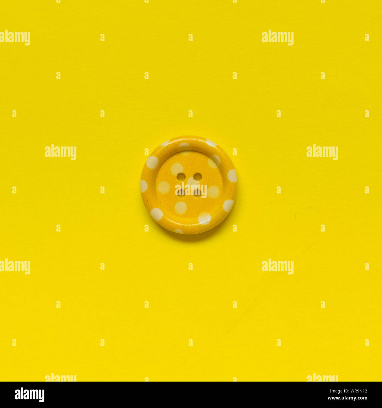 Giallo singolo pulsante cucitura con punti su sfondo giallo. Foto Stock