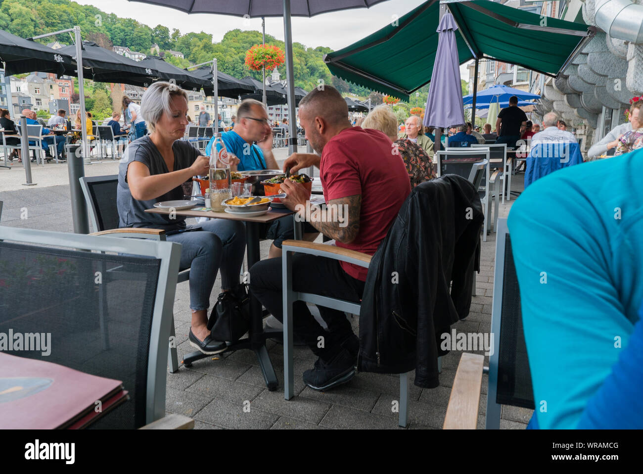 Dinant, Namur / Belgio - 11 agosto 2019: persone per mangiare fuori e mangiare tradizionale le cozze e le patatine fritte piatto 'Moules et Frites' a Dinant Foto Stock