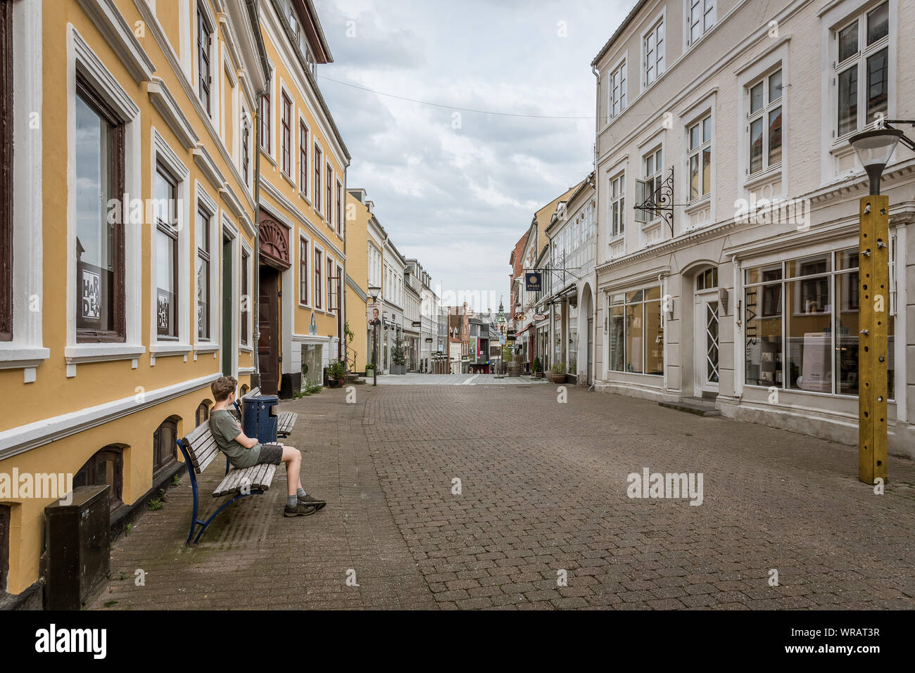 Un ragazzo seduto da solo in una strada spopolate di Svendborg, Danimarca, luglio 10, 2019 Foto Stock
