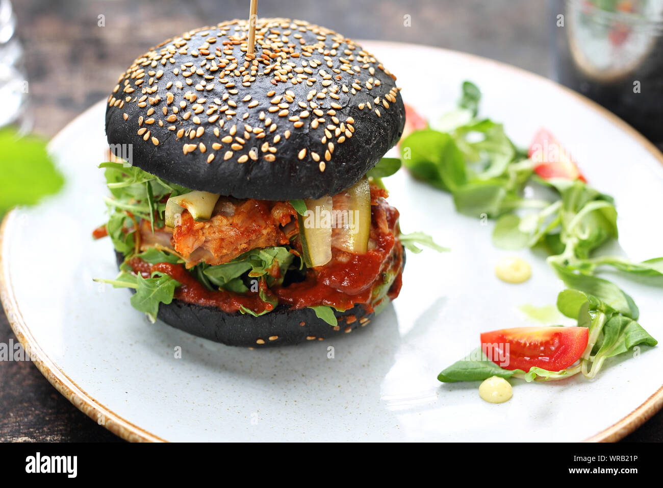 Burger in una black bun con carne tritata, cetriolo sottaceto e ketchup servita su una piastra. Foto Stock