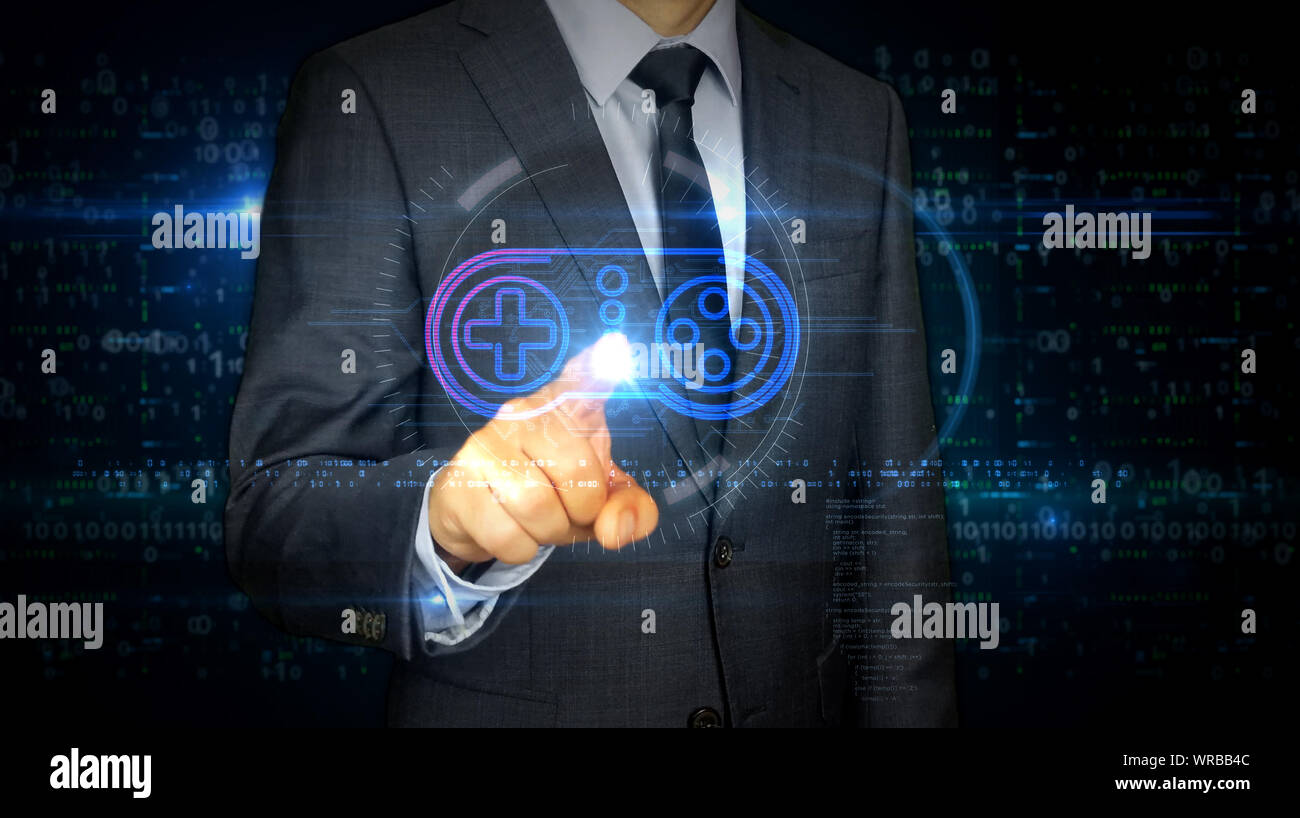 Un imprenditore in un vestito touch screen con un game pad simbolo ologramma. Uomo con mano sul display virtuale di interfaccia. Videogame, 5G, gioco e gioco online futu Foto Stock