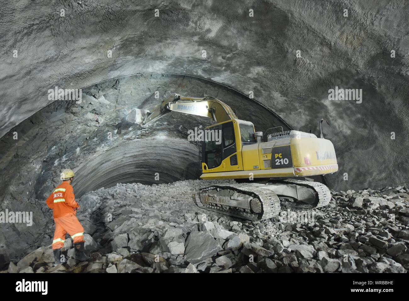 Un Cinese lavoratore edile orologi un escavatore trattare con il tetto durante un rischio di distacco dopo il percorso di sinistra del Changchengwu Tunn Foto Stock