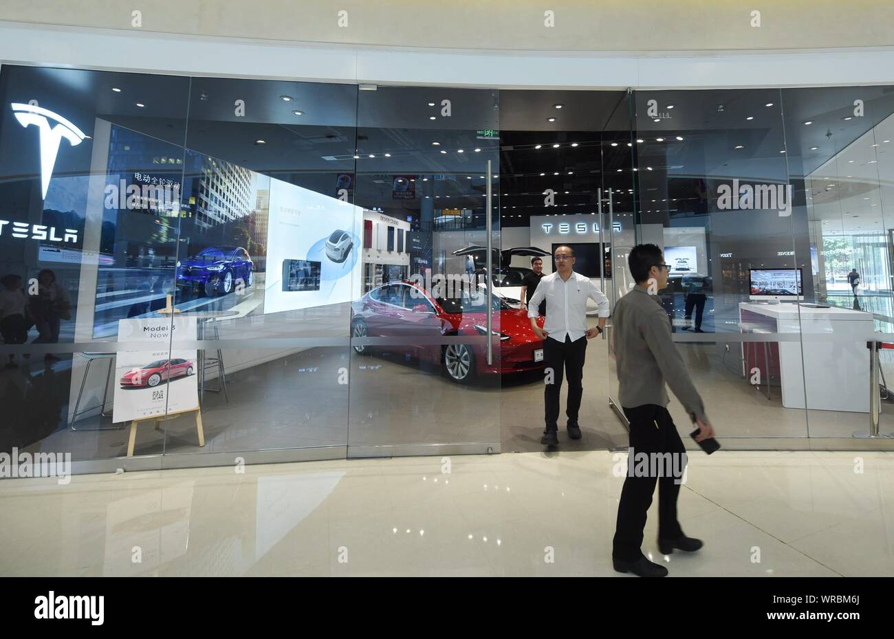 * * * * FILE acquirenti cinesi a piedi passato una Tesla store presso un centro commerciale per lo shopping nella città di Hangzhou, a est della Cina di Provincia dello Zhejiang il 14 maggio, 2019. Noi electric Foto Stock