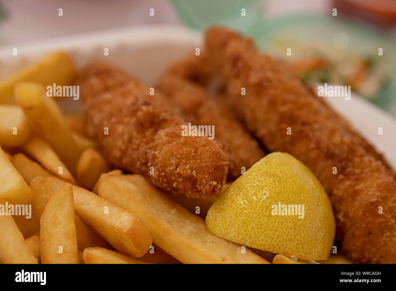 Patate fritte e fette di deep-pesce fritto con una fettina di limone close-up Foto Stock
