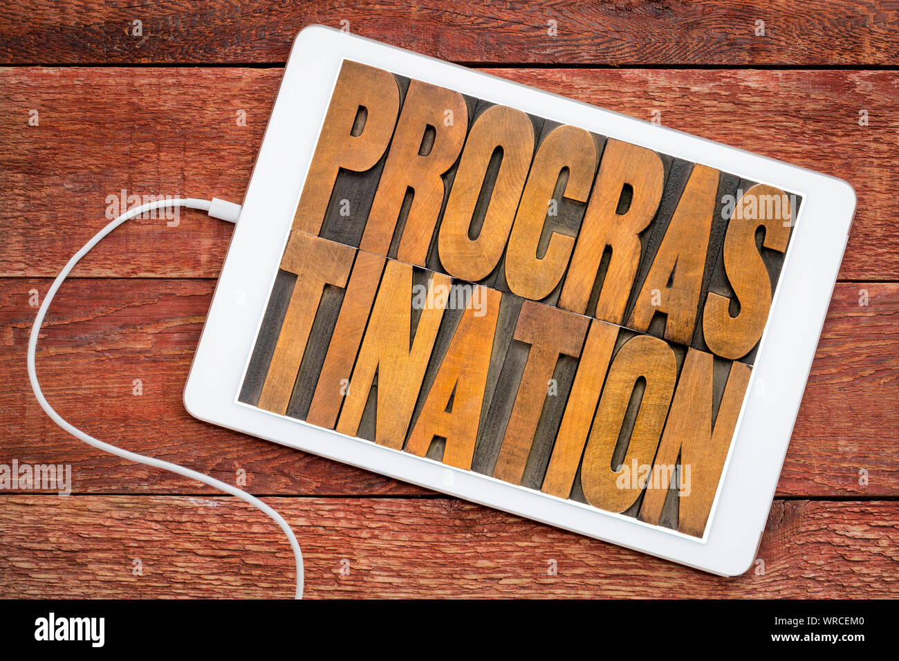 La procrastinazione parola abstract in rilievografia vintage tipo di legno su uno schermo di tavoletta digitale, l'efficienza e il concetto di produttività Foto Stock