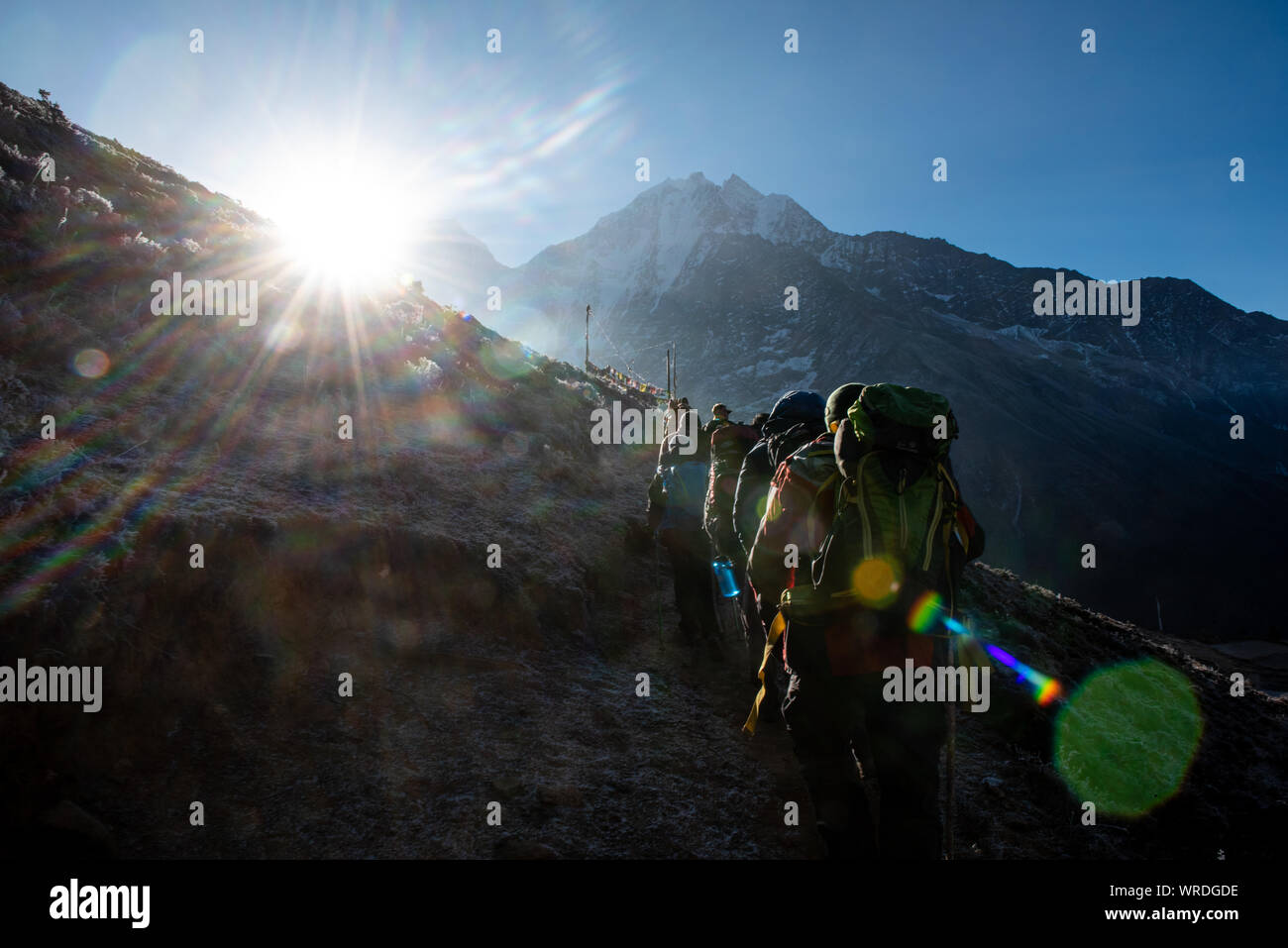 Sun trafigge il sole come gli escursionisti a piedi fino alla cima di una collina Foto Stock