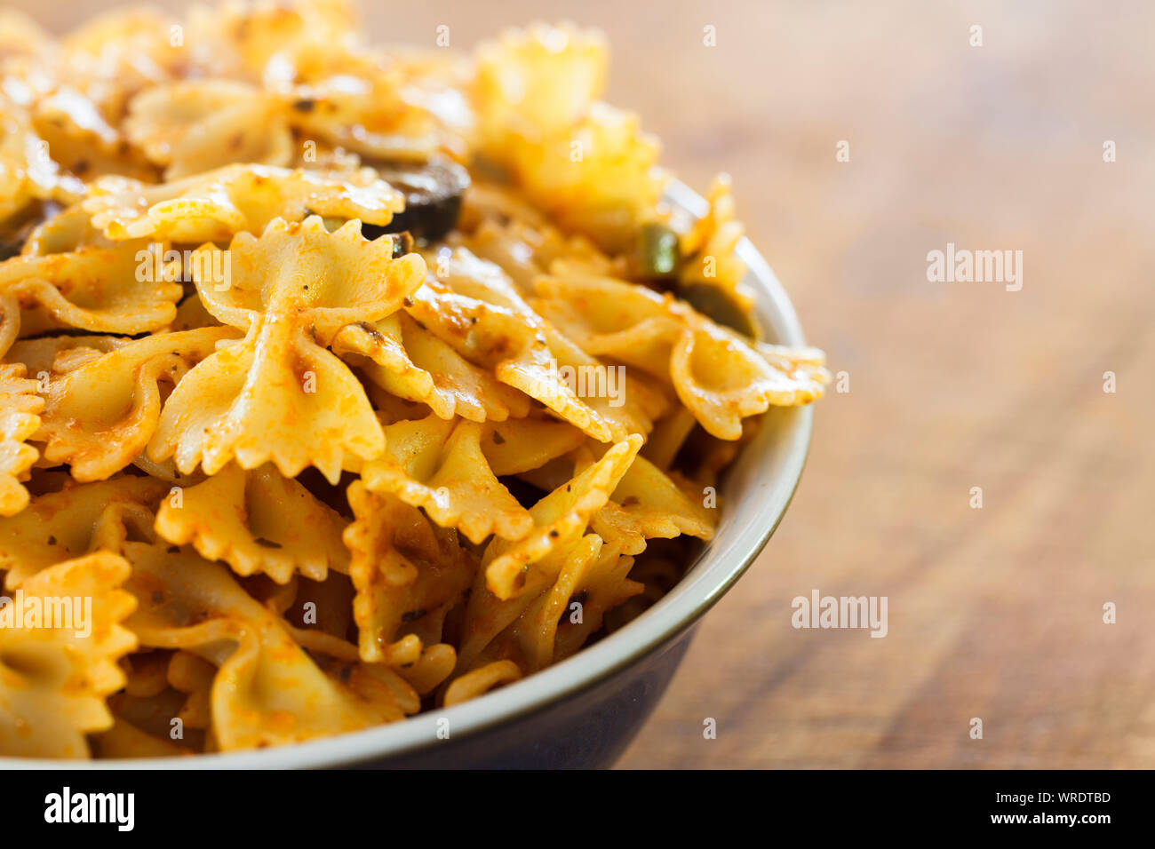 Recipiente di cottura bow tie-in pasta o farfalle di pasta in una fresca pesto, close up Foto Stock