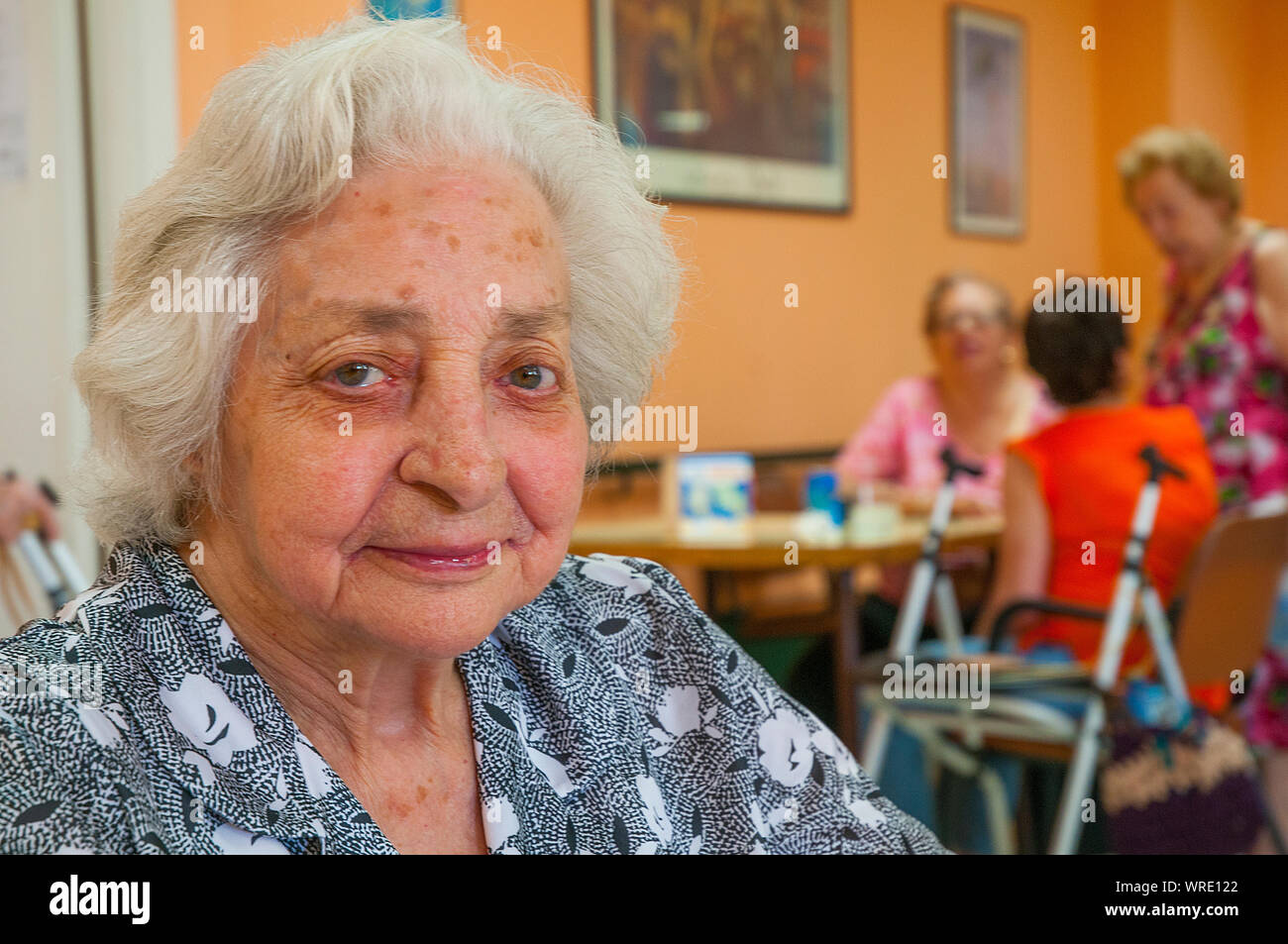 Old Lady in una casa di cura, sorridente e guardando la telecamera. Foto Stock