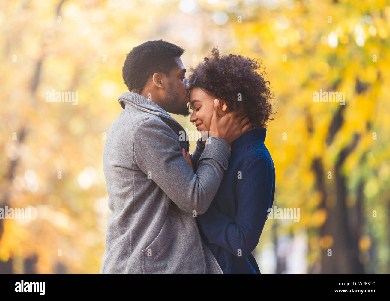 Nero amorevole guy teneramente baciando la sua fronte donna Foto Stock