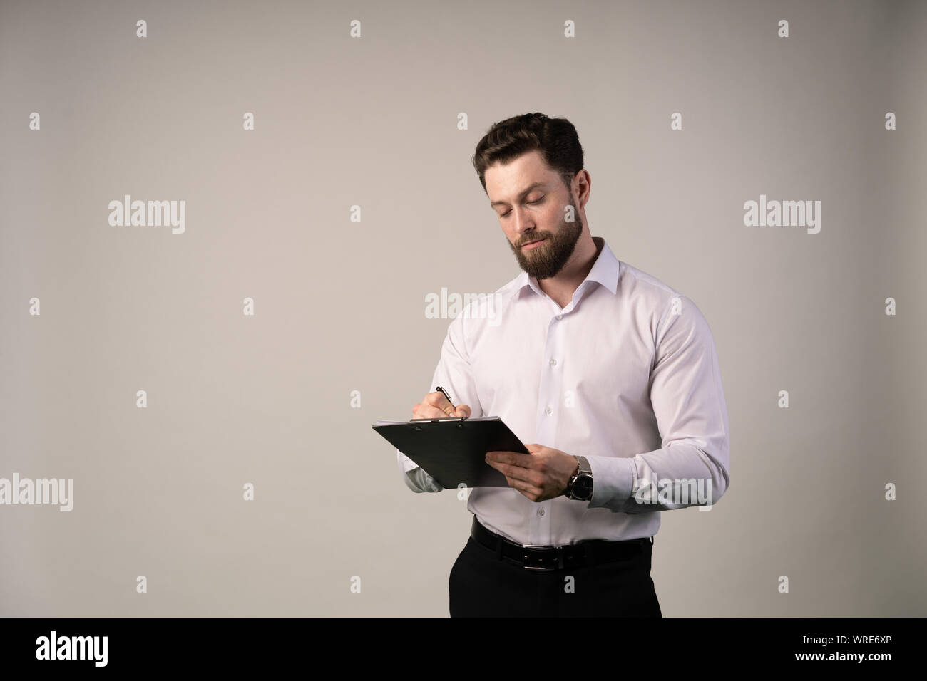 La mezza età, 30-40s imprenditore firma contratto ufficiale o riempimento di documento aziendale con una penna, lavorando in ufficio moderno con tazza di caffè, vicino u Foto Stock