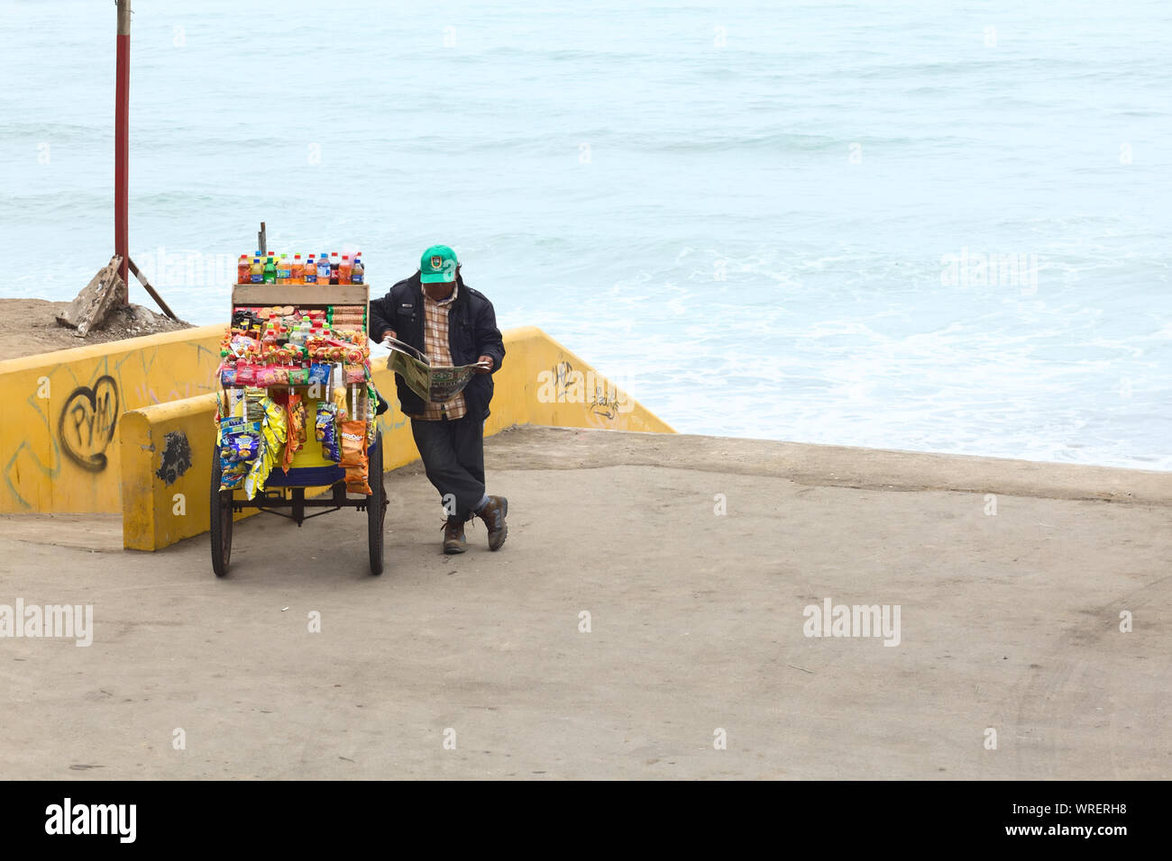 LIMA, Perù - luglio 5, 2013: persona non identificata la lettura di un quotidiano a snack carrello riempito con chip, dolciumi e bevande sulla costa di Barranco Foto Stock
