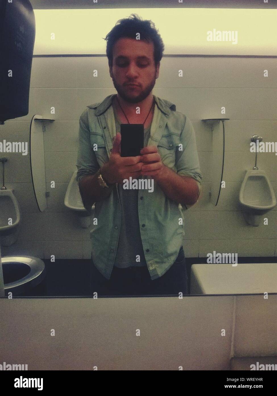 La riflessione di uomo bello tenendo Selfie nella toilette pubblica sullo  specchio Foto stock - Alamy