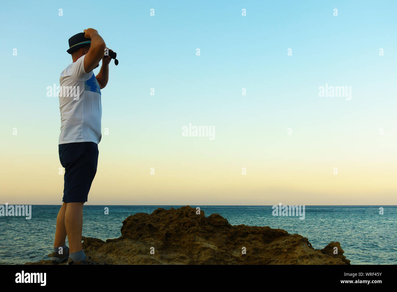 L'uomo guarda attraverso un telescopio al mare blu Foto Stock