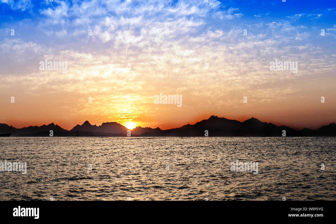 Bel tramonto panorama su silhouette di montagne e mare Foto Stock