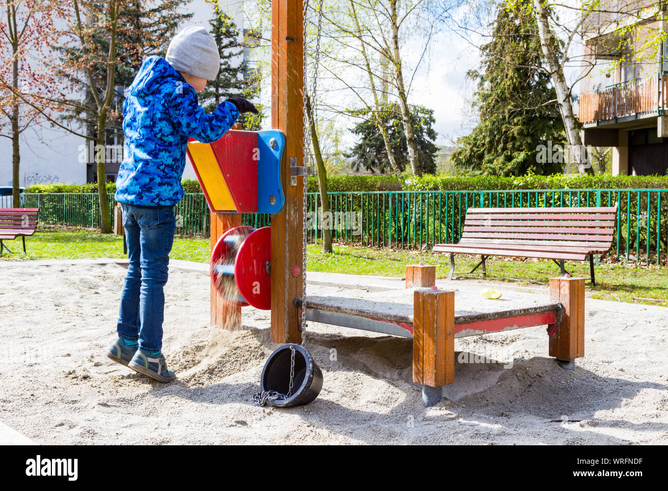 Bambino giocando in piedi in punta di piedi in sandbox presso il parco giochi Foto Stock
