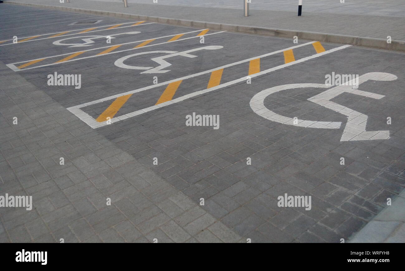 Assegnato un parcheggio per disabili per un pubblico parcheggio commerciale di colore giallo e con righe bianche Foto Stock