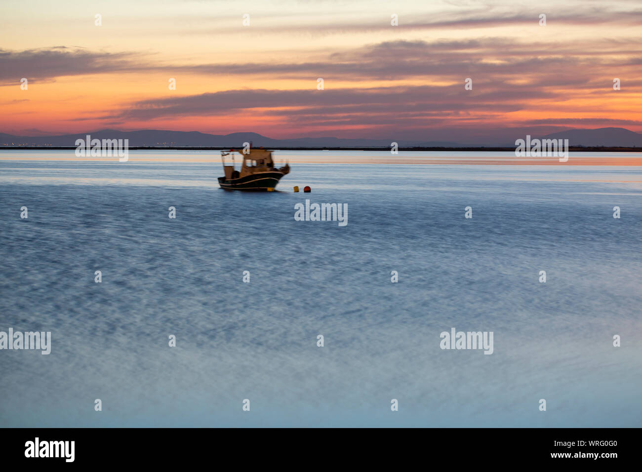 Una barca a vela con Misty tramonto e di riflessione sull'acqua Foto Stock