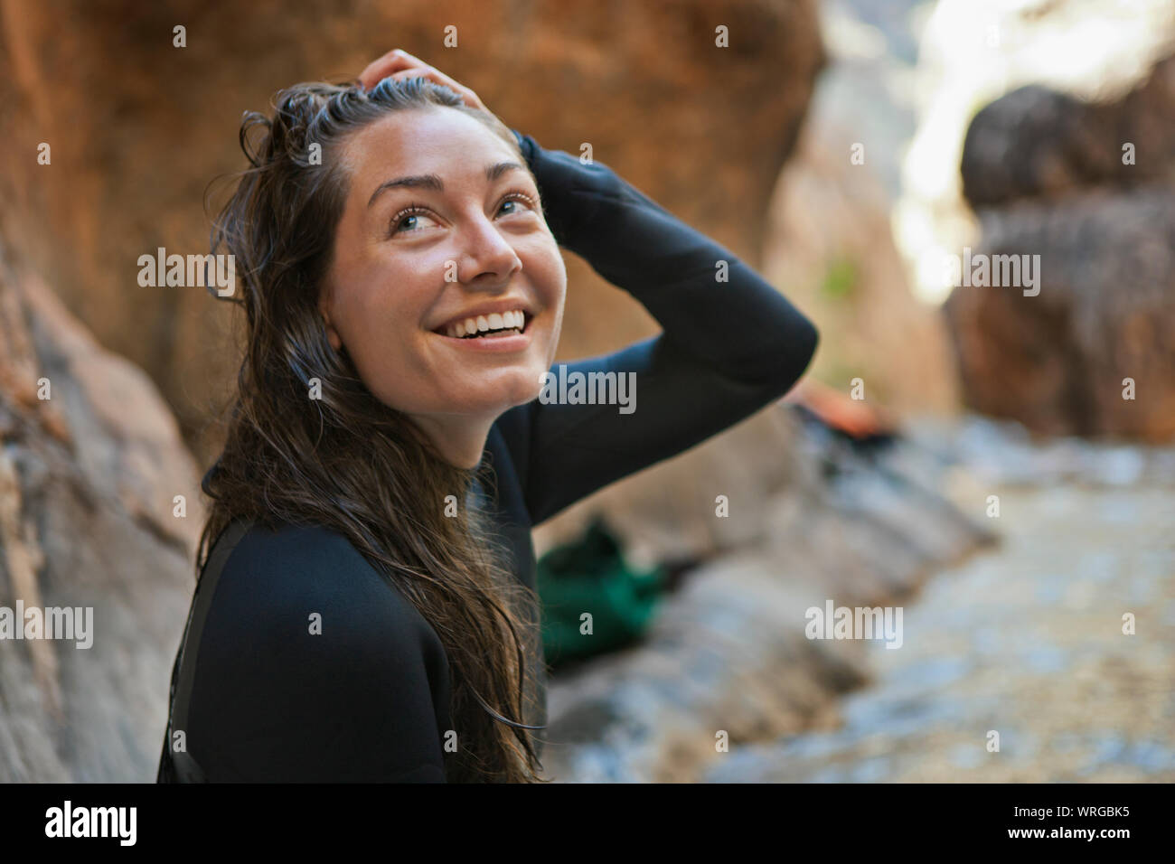 Sorridente giovane donna in esecuzione la sua mano attraverso i suoi capelli. Foto Stock