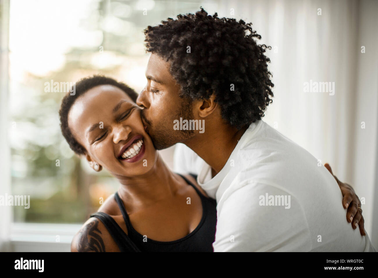 Affettuosa giovane baciare la sua ragazza sulla guancia. Foto Stock