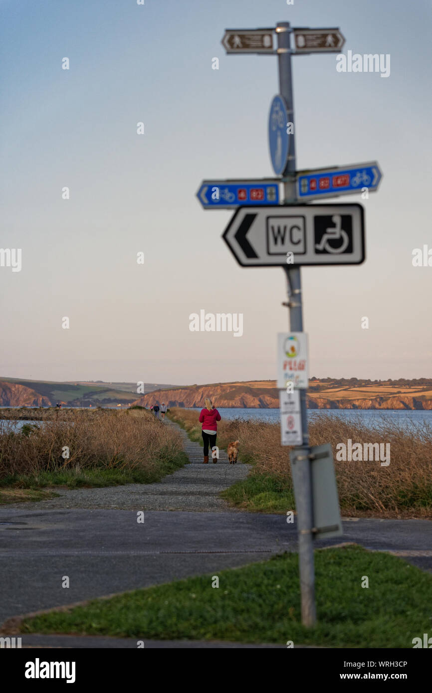 Una donna sola passeggiate sul lungomare di Fishguard, Wales, Regno Unito. Mercoledì 28 Agosto 2019 Foto Stock