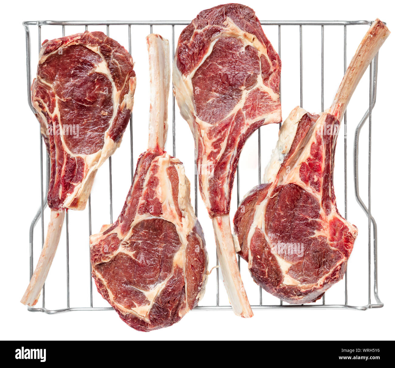 Vista dall'alto di quattro frenched osso nella carne di vitello costolette di tomahawk invecchiamento a secco su un acciaio inossidabile rack. Foto Stock