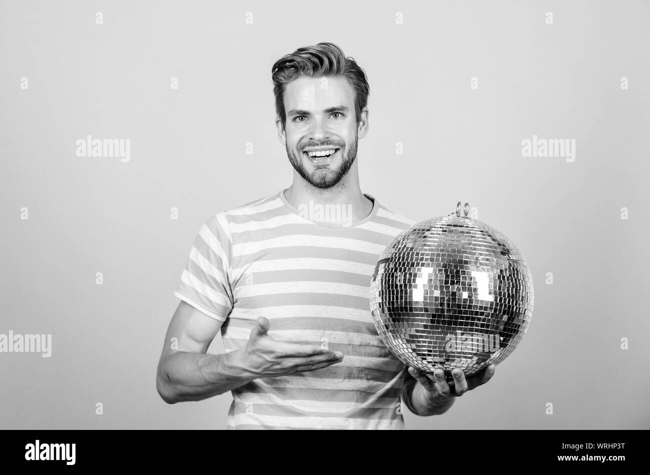 Allegro dj uomo. Uomo bello tenere palla da discoteca. Danze da discoteca night club. Musica retrò. Ragazzo che vi invitano a parte. Migliaia di minuscoli specchi che riflettono la creazione delle luci di atmosfera da discoteca. Come circa la parte. Foto Stock