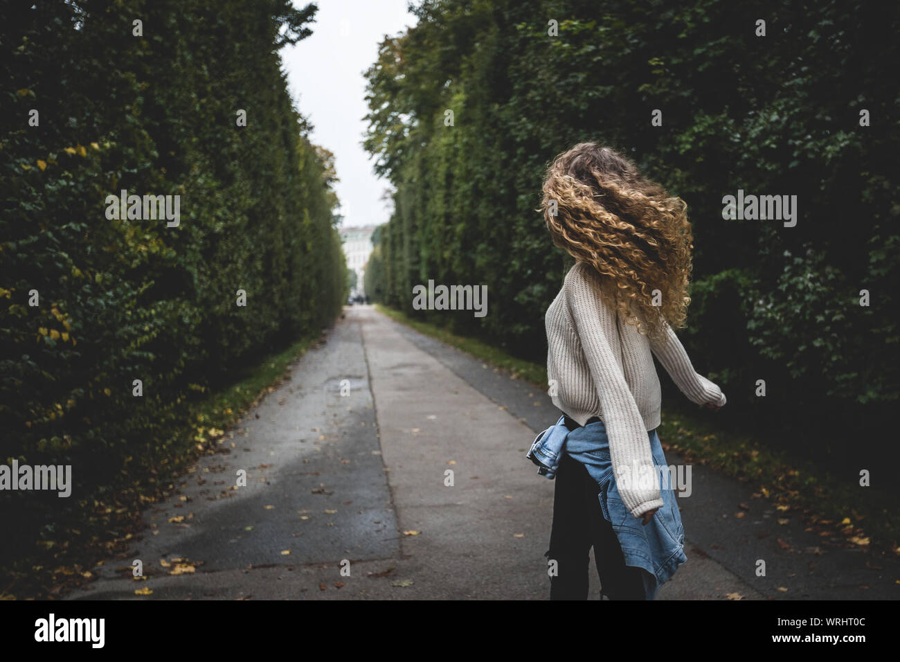 Donna con capelli ricci camminando sul sentiero fra gli alberi Foto Stock