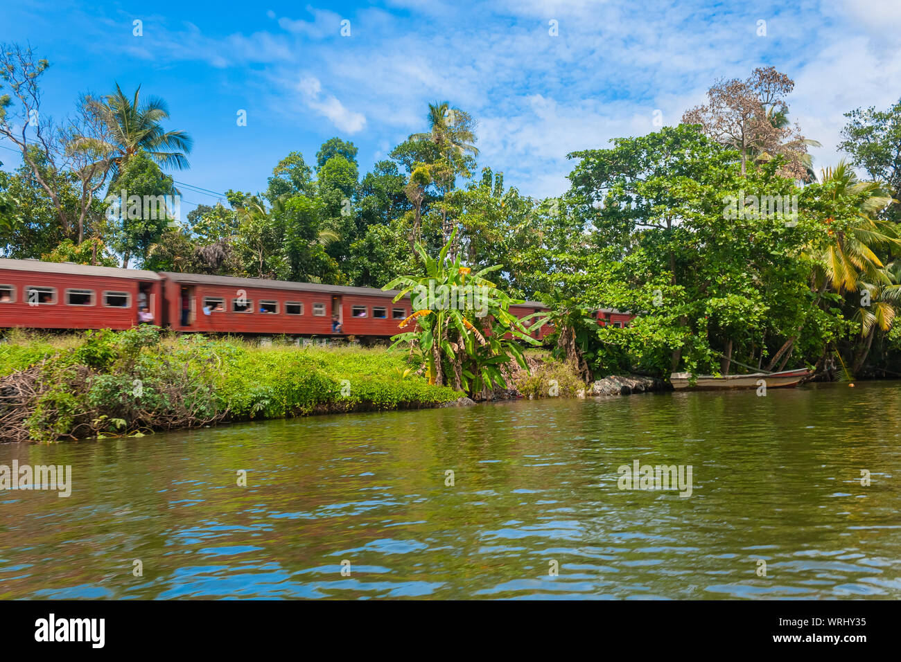 Il treno passa lungo il fiume. Balapitiya, Sri Lanka Foto Stock