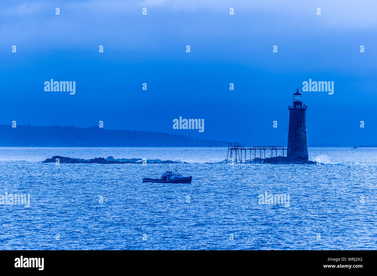 Mattina blu con una lobster boat passando dalla Ram battuta Island Lighthouse, Portland, Maine, Stati Uniti d'America. Foto Stock