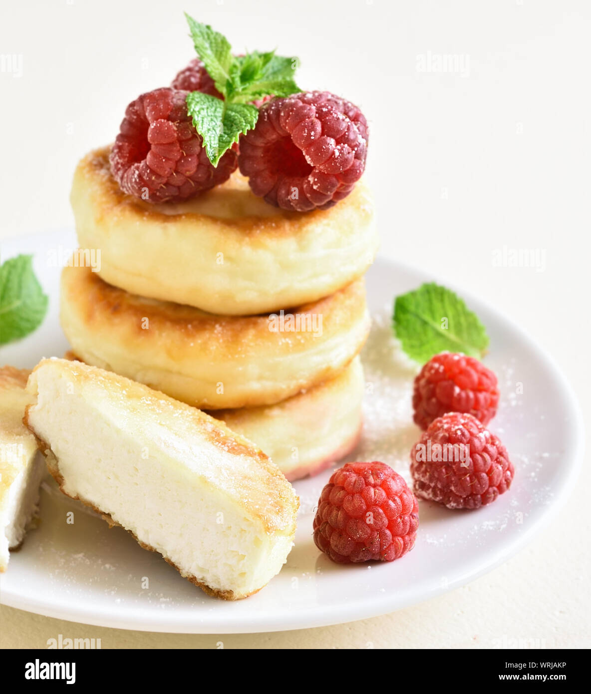 Chiusura del cottage cheese pancakes, frittelle di cagliata con lamponi freschi sulla piastra al di sopra della luce di sfondo di pietra. Foto Stock