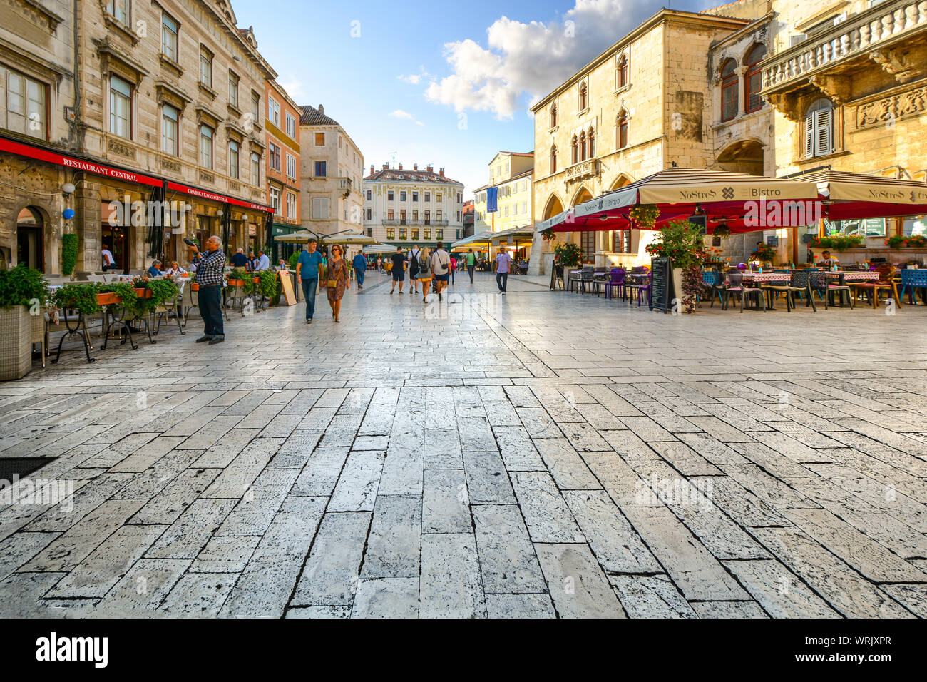I turisti e i locali passano da negozi e caffè mentre iniziano la loro giornata a Piazza del Popolo nel palazzo di Diocleziano sezione di Spalato Croazia Foto Stock