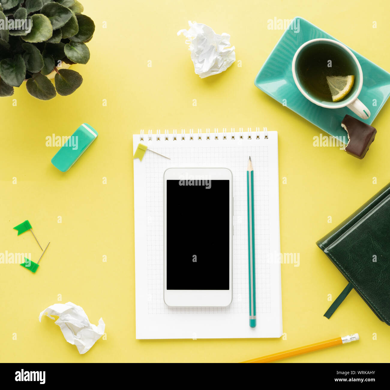Pulire stilizzata ufficio giallo scrivania con lo smartphone, notepad, matita e tè, area di lavoro progettazione, simulazione, vista dall'alto, piana, laici spazio copia, primo piano Foto Stock