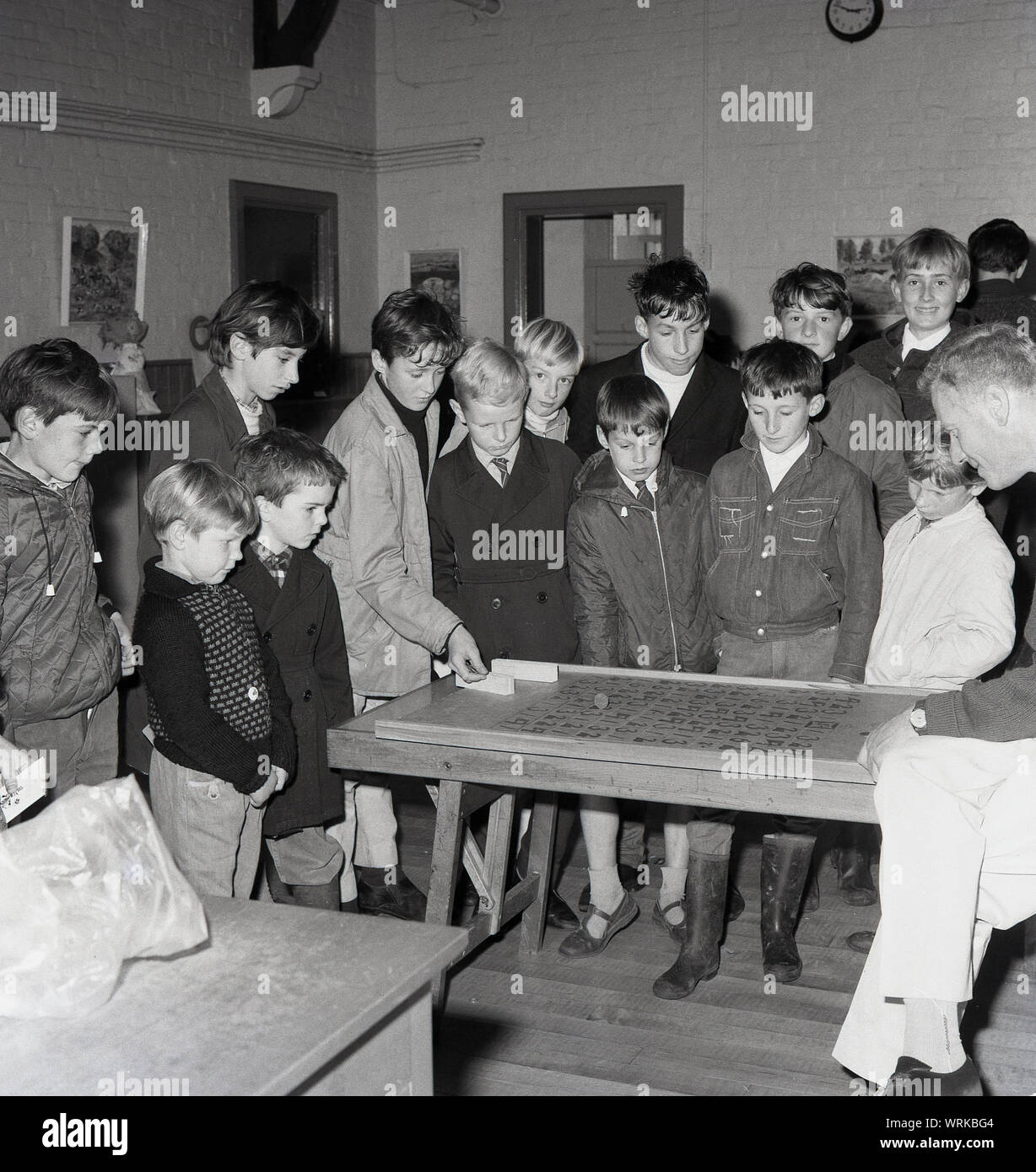 1967, storico, un gruppo di ragazzi in una scuola fund raising accozzaglia di vendita o bazaar, giocando un shove un centesimo (moneta) gioco su una tavola di legno, Inghilterra, Regno Unito. Foto Stock