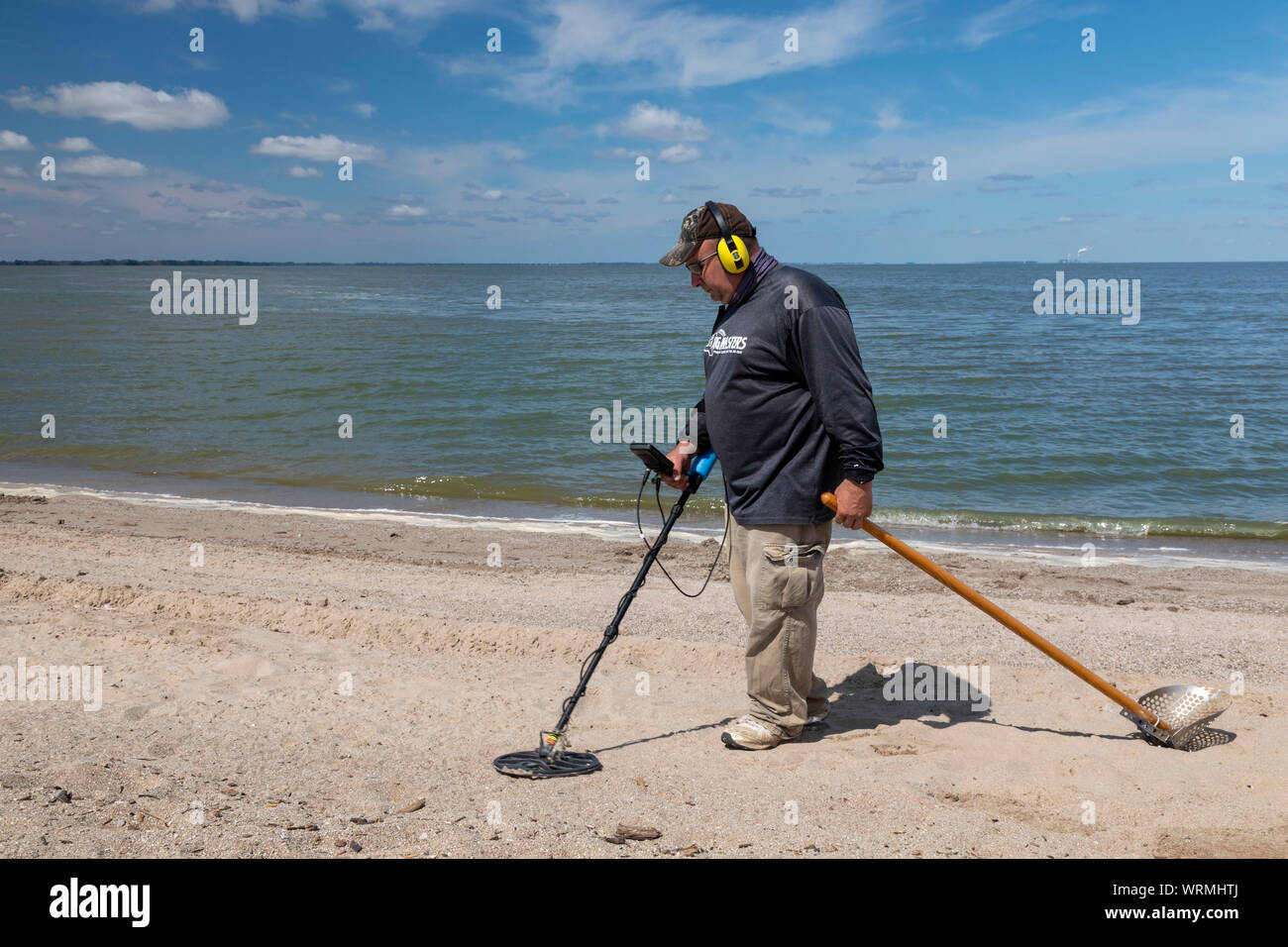 Oregon, Ohio - un uomo utilizza un rivelatore di metalli per la ricerca di monete e di altri metalli sulla spiaggia di Baia di Maumee parco dello stato. Foto Stock