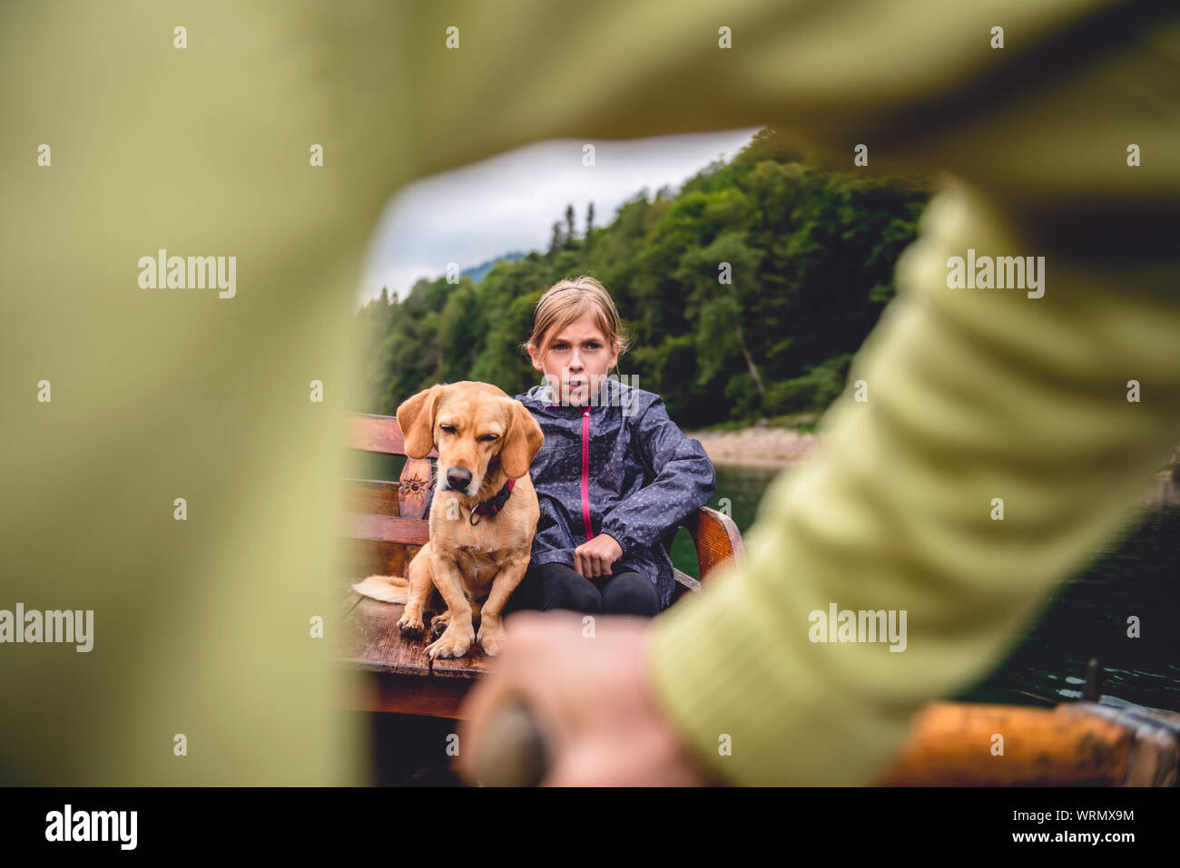 Madre e figlia con un piccolo cane giallo remare una barca su un lago di montagna Foto Stock