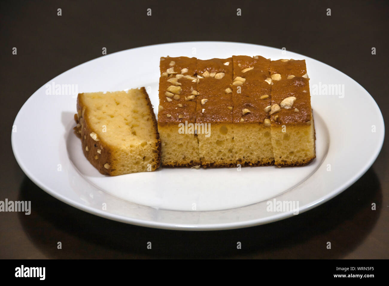 A tagliare la torta con anacardi su una piastra bianca Foto Stock