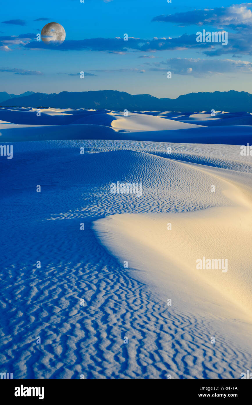 Immagine creata digitalmente di una luna crescente oltre nei toni del blu dune di sabbia. Foto Stock