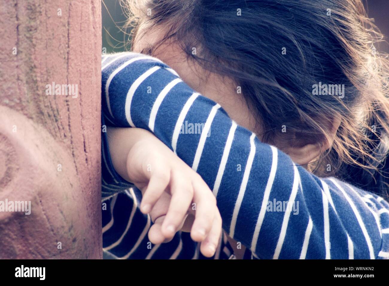 Close-up di una ragazza che ricopre la faccia mentre si gioca a nascondino Foto Stock