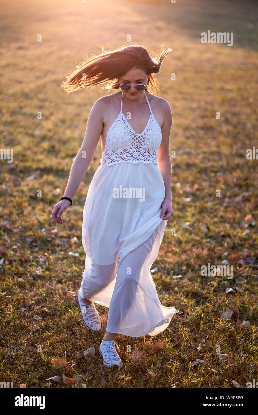 Giovane sposa in posa da soli nel campo al tramonto Foto Stock