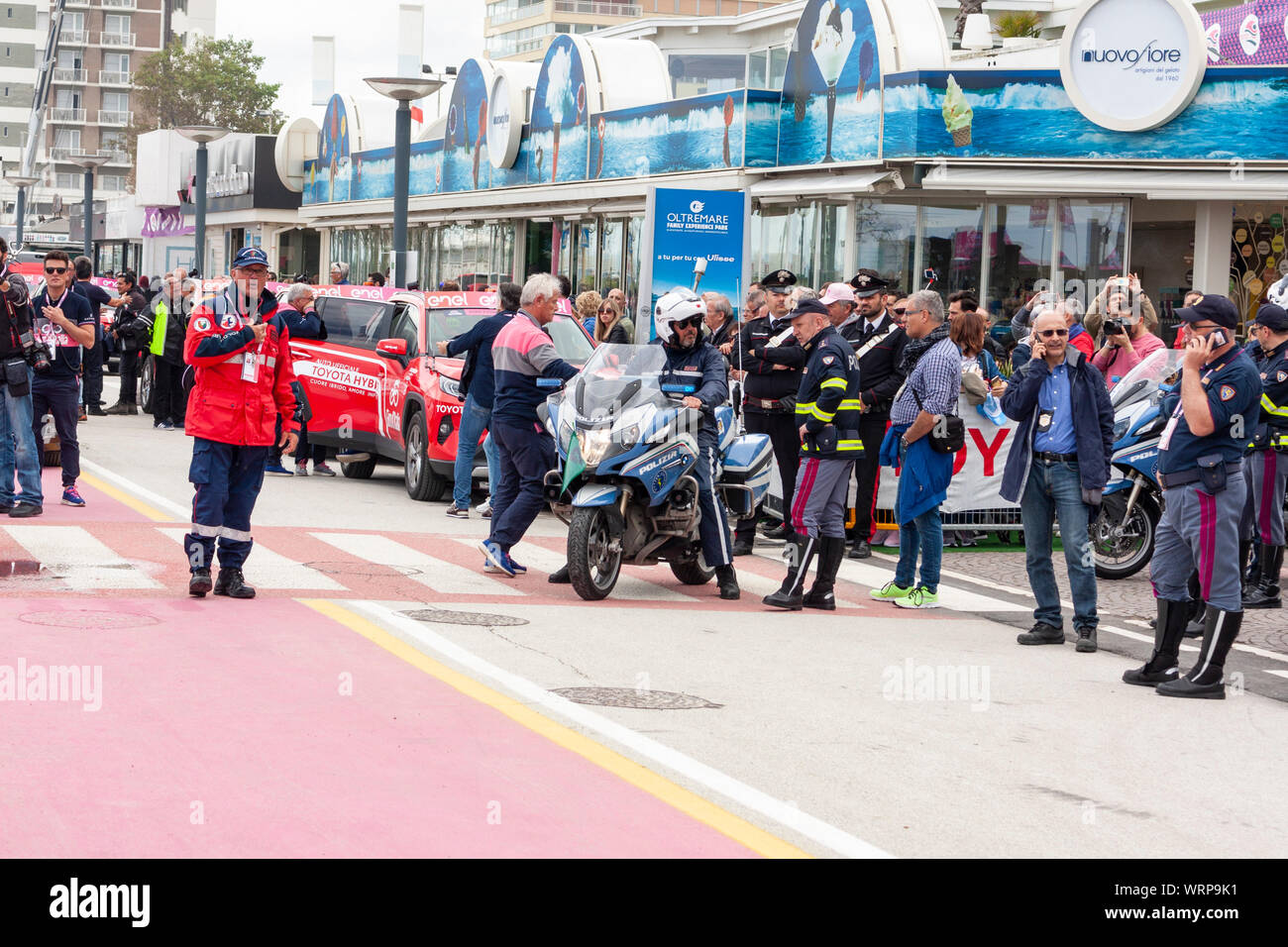 Gli ufficiali di gara e forze di polizia stanno intorno e chat prima fase nove del 2019 il Giro d'Italia. Riccione, Italia Foto Stock
