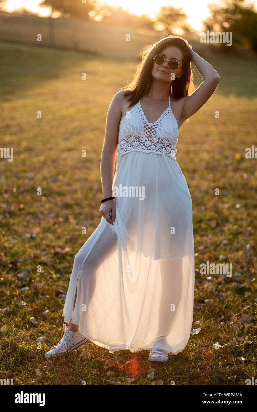 Giovane sposa in posa da soli nel campo al tramonto Foto Stock