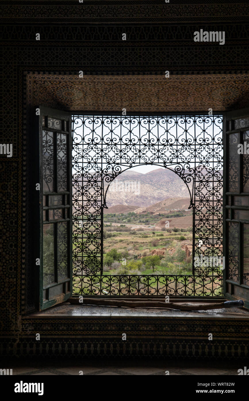 Guardare fuori per le montagne e la vallata sottostante da una finestra ornata in Marocco Foto Stock