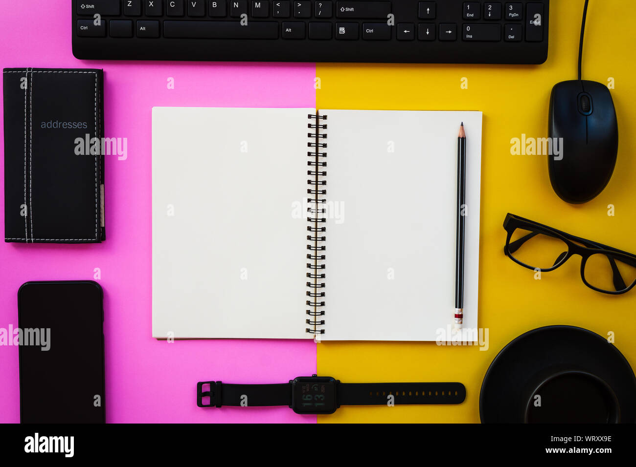 Vuoto il blocco note di bianco con il nero ufficio e accessori personali isolato in due tonalità di rosa e sfondo giallo, Business ispirazione e motivazione co Foto Stock