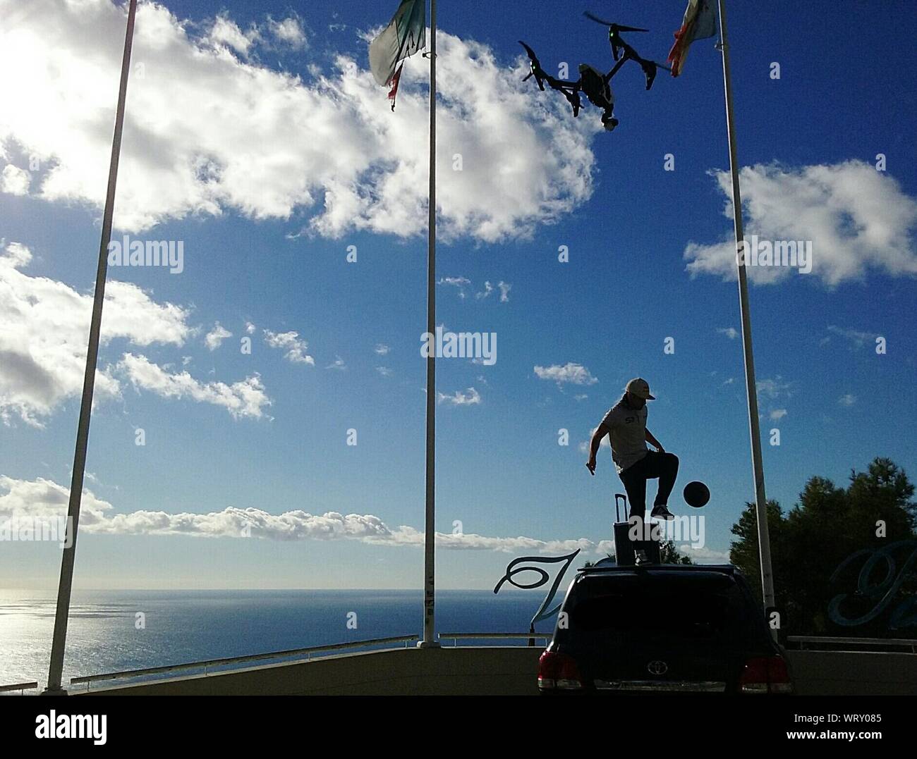Uomo che giocano a calcio sulla parte superiore della macchina dal mare contro Sky Foto Stock