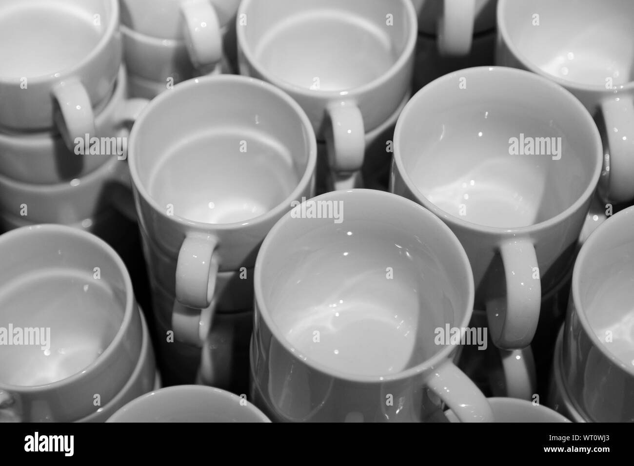 Un sacco di bianco pulito per le tazze da tè e caffè impilate una sull'altra Foto Stock