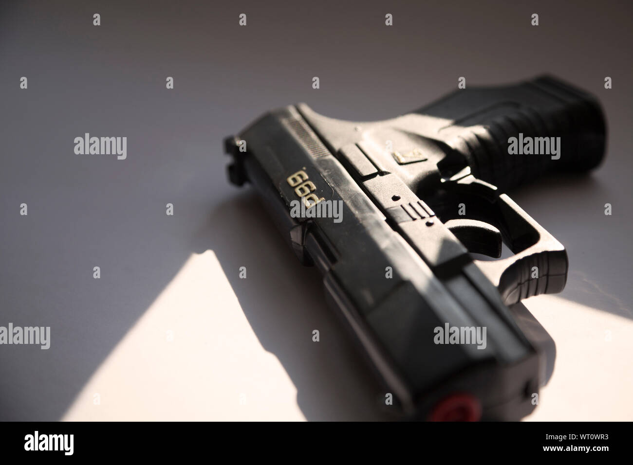 Umea, Svezia - 4 Settembre 2019: una pistola nera si trova nella finestra con la luce del sole in streaming dalla finestra più vicina Foto Stock