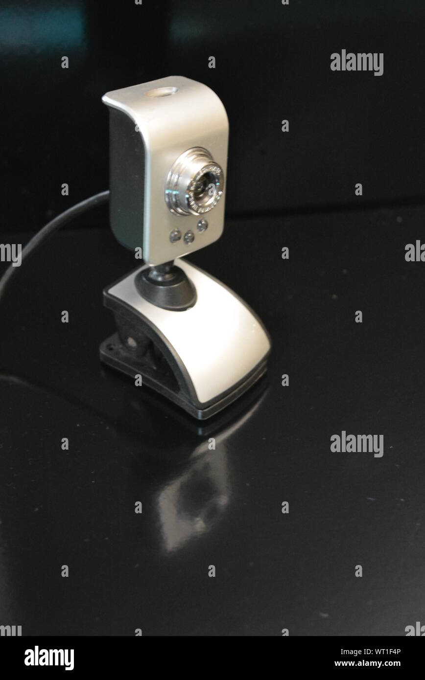 Una webcam color argento per il computer con clip per il monitor si trova su una superficie nera opaca con riflesso. Foto Stock