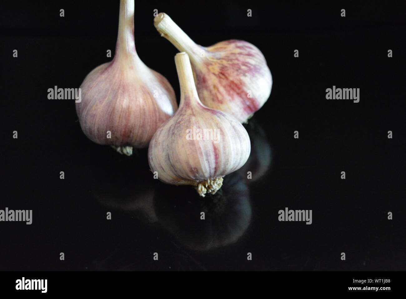 Verdure fresche, tre teste di vitello adagiate su una superficie nera lucida con riflessi ripetuti. Foto Stock