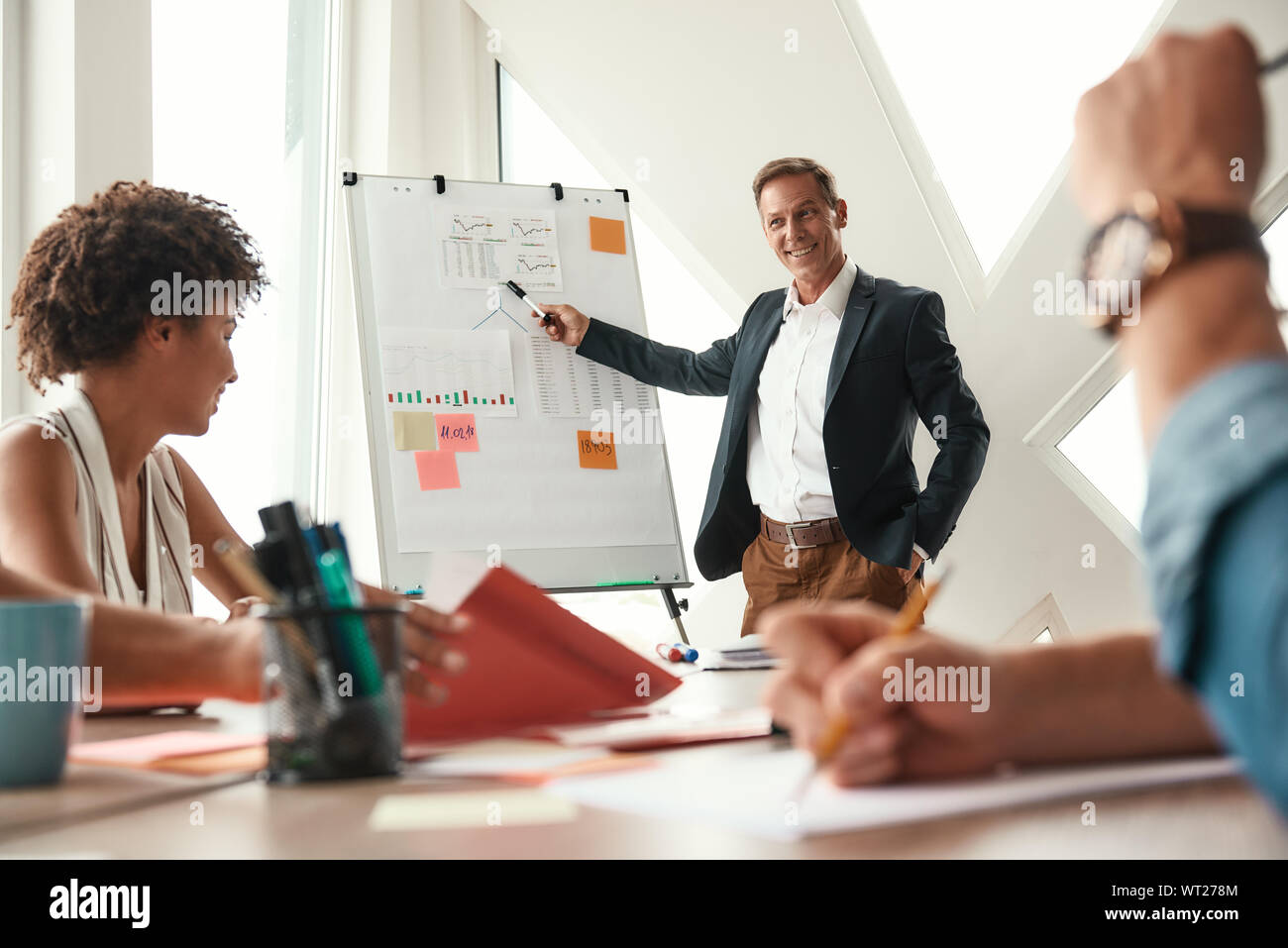 Abbiamo grandi risultati. Imprenditore maturo in piedi vicino a lavagna e spiegare qualcosa ai suoi colleghi. Il lavoro di squadra. Sale riunioni Foto Stock